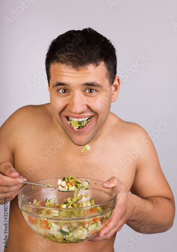 Photo: Young happy smiling man eating salad Young happy smiling man eating salad