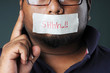 Man with silent message sticker at his mouth and hand shows warn