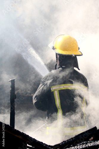 Photo: Fireman Putting out a House Fire Fireman Putting out a House Fire