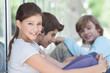 Smiling girl sitting outdoors with boys in the background