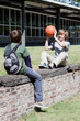 Two boys playing with basketball on stone wall