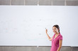 Smiling student standing at whiteboard with formula