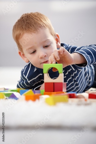 Photo: Sweet gingerish boy building tower at home Sweet gingerish boy building tower at home