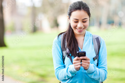 Photo: Asian student texting on the phone Asian student texting on the phone
