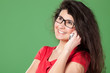 Portrait of young smiley female in eye-glasses talking on phone