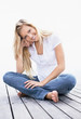 Smiling young female sitting crossed legs on a porch