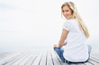 Casual female sitting on a wooden porch and smiling at you