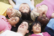 Happy teenagers lying on grass with their head to head
