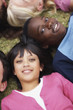 Happy girl lying on grass head to head with friends