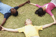 Smiling teenagers lying on grass and making a triangle