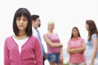 Depressed young girl standing away from a group of friends