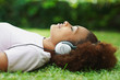 Profile view of a girl lying on grass and listening to music