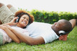 Happy couple listening to music together on the grass outdoors
