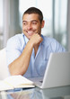 Young business man looking away while working on laptop