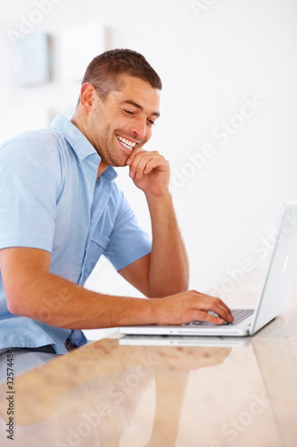 Photo: Happy young man working on laptop Happy young man working on laptop