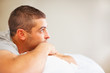 Thoughtful young guy lying on bed