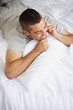 Young man lying on bed and talking on mobile