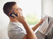 Foto: Young man talking on mobile with newspaper Young man talking on mobile with newspaper