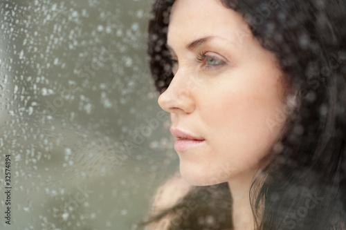 Foto: Cute female behind glass with water drops on it Cute female behind glass with water drops on it