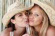 Closeup of two females wearing hats with beer bottles