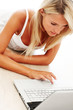 Pretty young woman lying on floor and using laptop