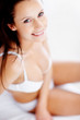Cute happy woman in lingerie sitting on bed