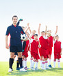 Portrait of coach with cheering soccer team on field - copyspace