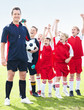 Confident soccer coach leads his excited little players on field