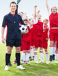 Soccer coach with excited team players on field