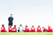 Coach in discussion with soccer players as they sit in a row
