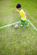 Little boy kicking football on playground
