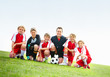 Coach with his football team kneels in row on field - copyspace
