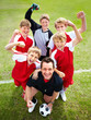 Excited soccer team with coach cheering on field
