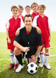 Happy soccer coach with confident team in red on field