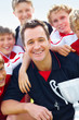 Closeup of a smiling coach holding trophy with successful team