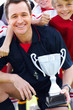 Successful coach holding trophy with his team