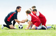 Soccer team with coach putting hands together before a match