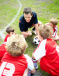 Football coach motivating little players before a match on field