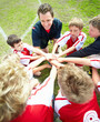 Football team with coach putting hands together before a match