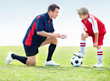 A coach instructing a soccer kid on field
