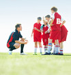 Little soccer players listening to their coach on field