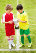Members of two different teams sharing a trophy on soccer field