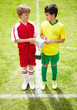 Members of two different teams holding a trophy on soccer field