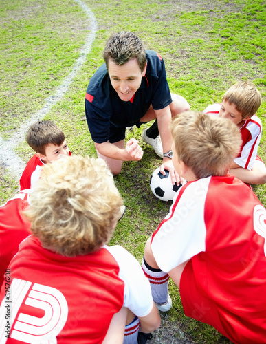 Foto: Football coach motivating little players before a match on field Football coach motivating little players before a match on field