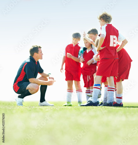 Photo: Little soccer players listening to their coach on field Little soccer players listening to their coach on field
