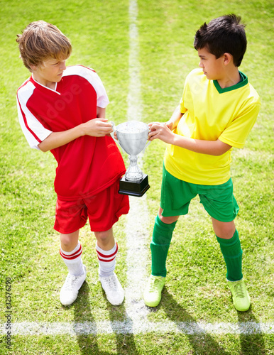 Foto: Players of two different soccer teams pulling a trophy Players of two different soccer teams pulling a trophy