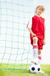 Confident Caucasian kid against net with football under foot