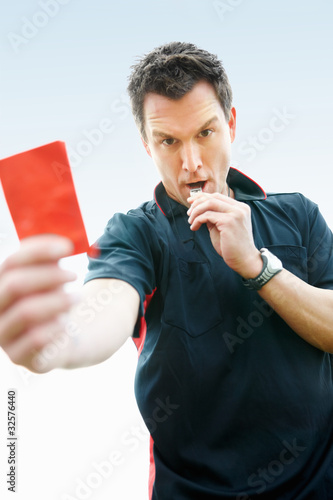Foto: Football referee showing you the red card against sky Football referee showing you the red card against sky