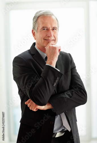 Photo: Confident mature business man with hand on chin Confident mature business man with hand on chin