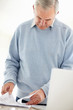 Senior man going through documents with a laptop